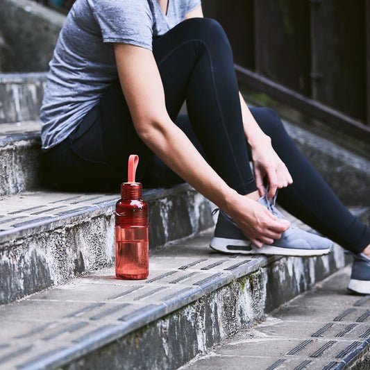 Person sitting on steps with a red water bottle next to them